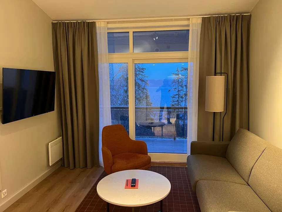 Hotellrom med beige gardiner foran et stort vindu