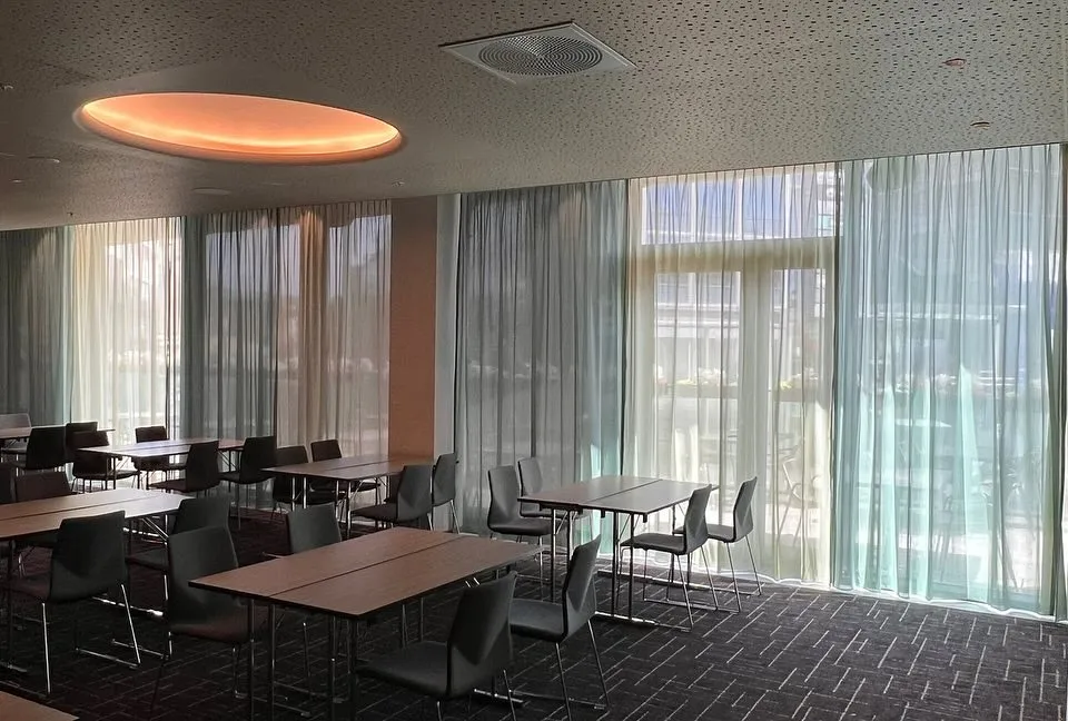 Møtesal med transparente gardiner foran store glassflater
