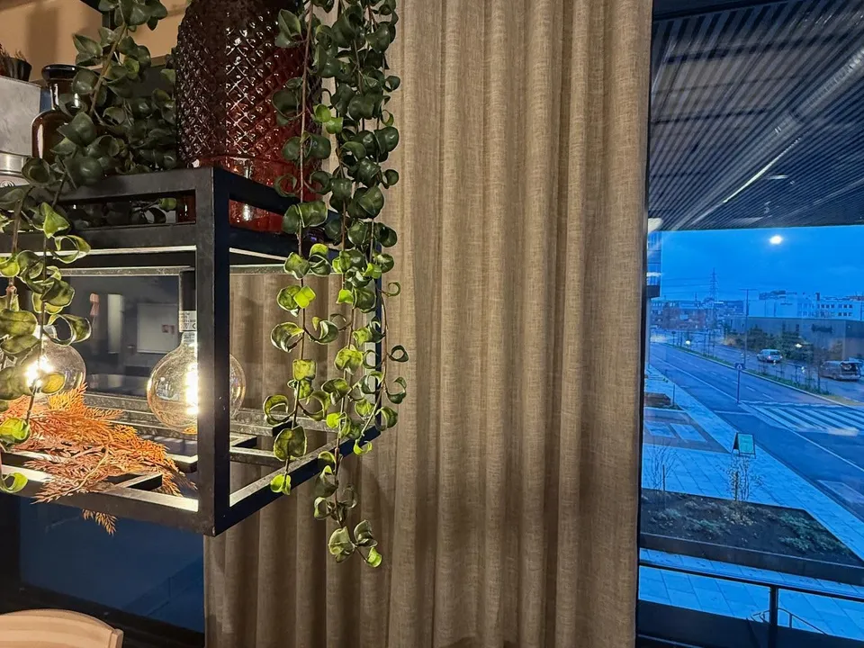 Restaurant med lingardiner ved en grønn plantevegg